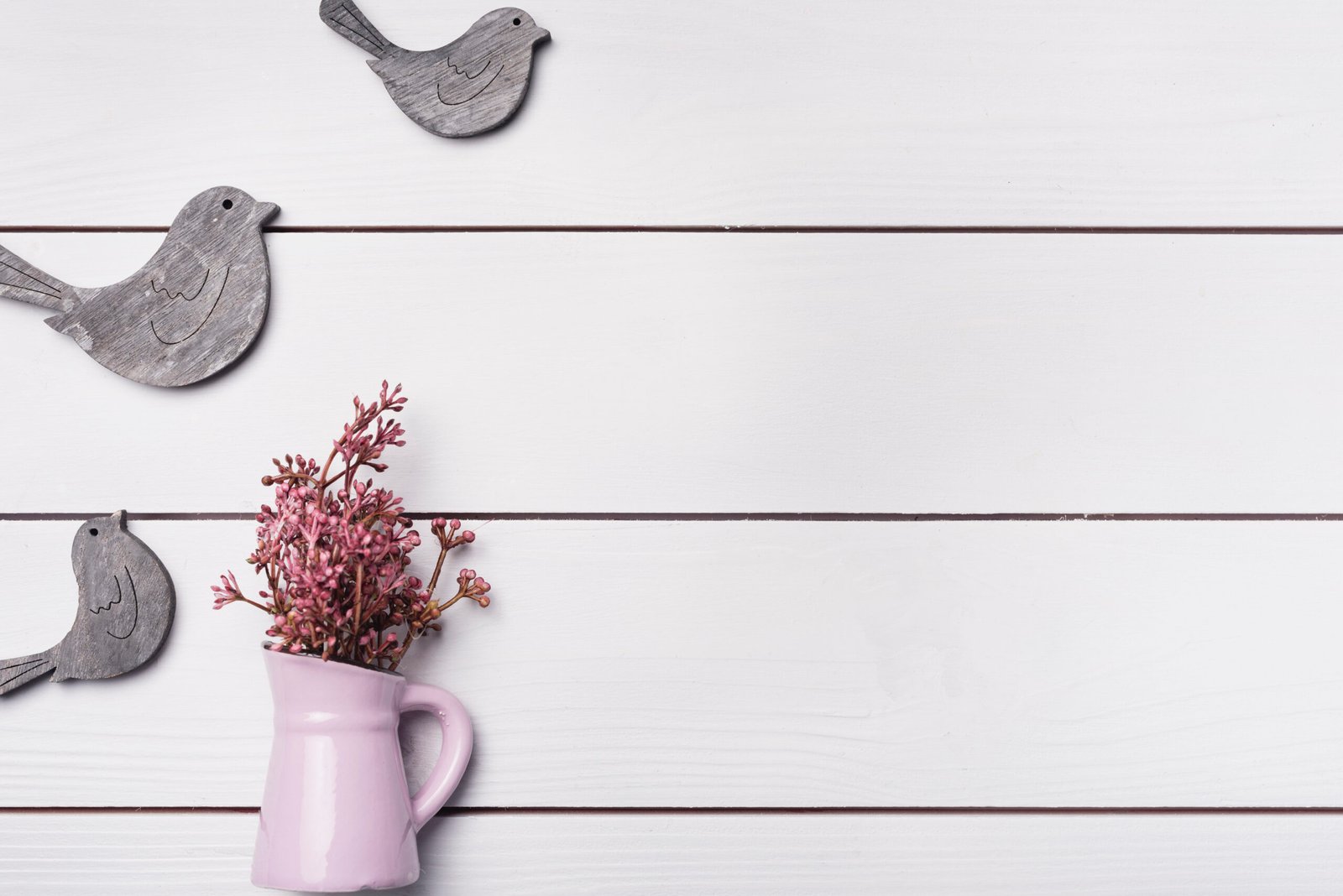 Dekoratives Stillleben mit Keramikvase, Holzvögeln und zarten Blumen – Matvana